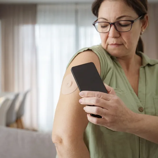 Middle aged woman checking her cgm with phone