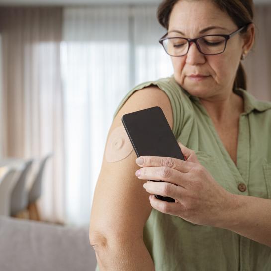 Middle aged woman checking her cgm with phone