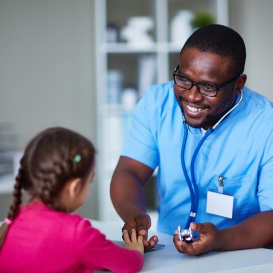 Smiling African American male school nurse explaining a stethoscope to a young female student