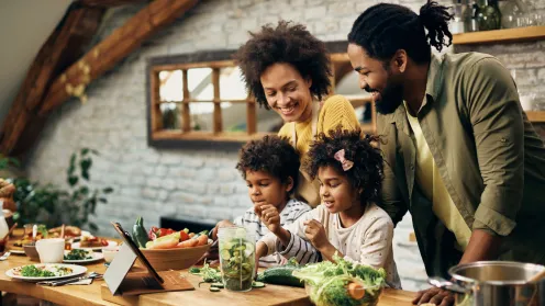 A happy family cooking veggies in a kitchen