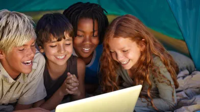 Kids in tent looking at laptop computer