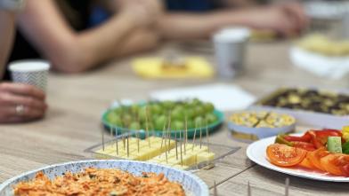a table full of finger food and snacks with people around it