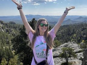 A woman on a mountain top with her arms raised.