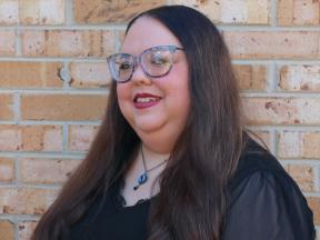 A woman standing in front of a brick wall.