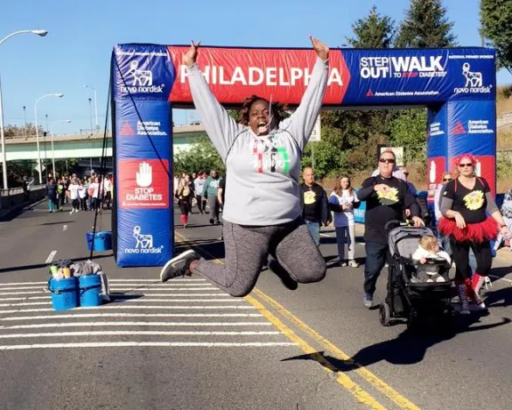 Person jumps in front of the Step Out Walk for Diabetes banner.