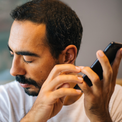 A man with low vision listens to audio reader on his phone