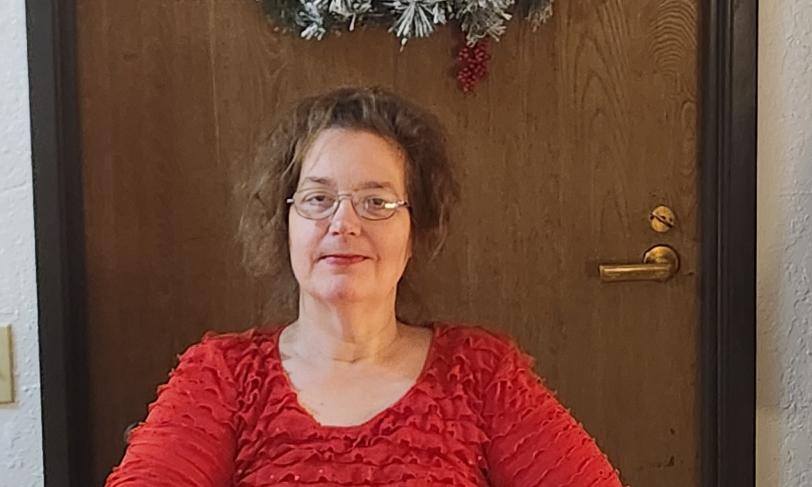 Photo of Christine sitting front of a door with a wreath.