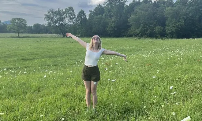 Woman with her arms spread out standing in a field