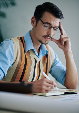 A man sits in front of a notebook and journals.