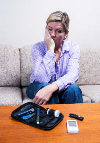 A woman looks sadly at her blood glucose monitor.