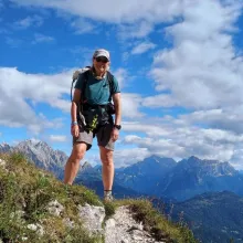 A woman standing on a mountain peak with a backpack.