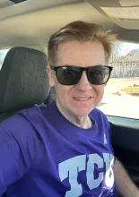 A man wearing sunglasses and a purple t-shirt.