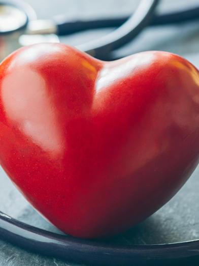 Red lacquered ceramic heart on table with stethoscope