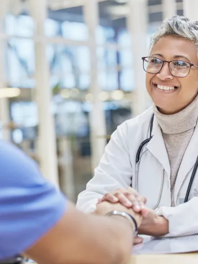 Smiling female physician holding hand of patient