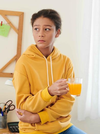 Sad teenage girl holding glass of orange juice